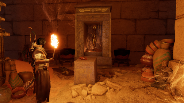 Bayek en una tumba con una antorcha en la mano derecha